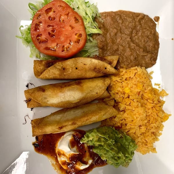 Sabor Maya's taquitos plate with rice, refried beans, lettuce, tomato, guacamole, and sour cream.