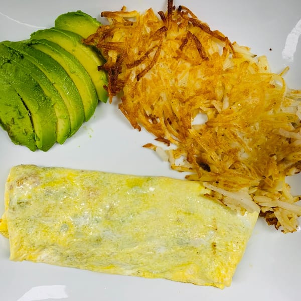 A Sabor Maya Mexican Cuisine breakfast plate with an omelet, hash browns, and sliced avocado.